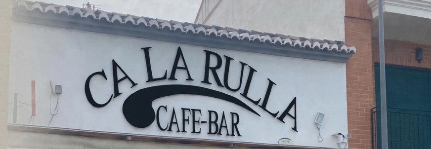 Rótulo de Ca la Rulla Café-Bar sobre la fachada blanca con teja árabe
